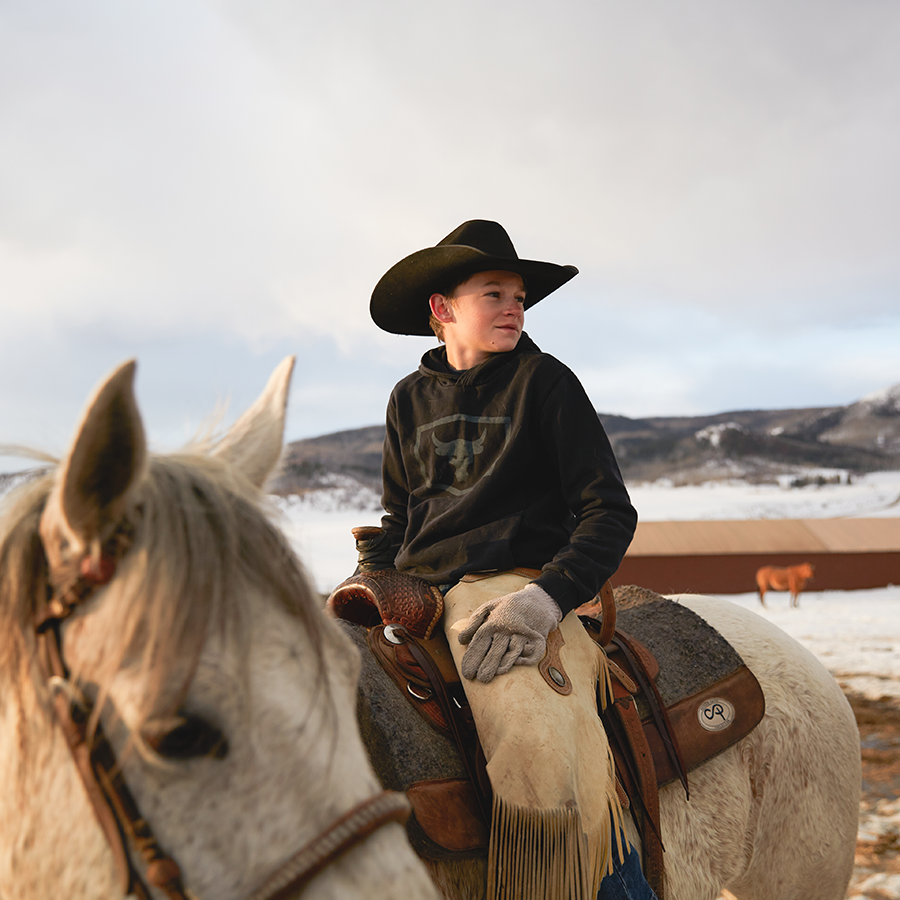 A boy sitting on a horse in the snow posing for a photo.